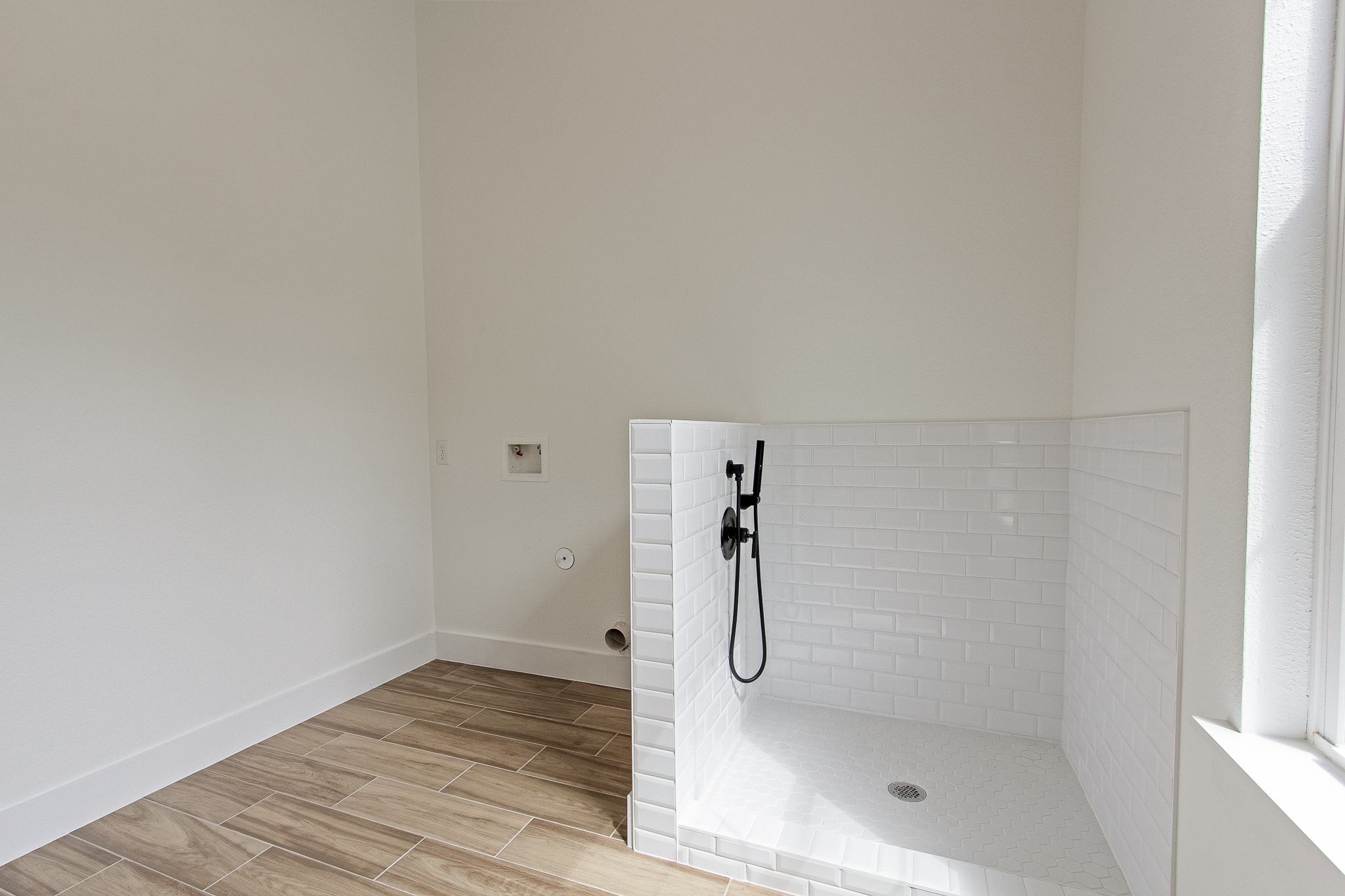 Subway-tile pet wash and wood-look tile floor in a Brixton custom home laundry room