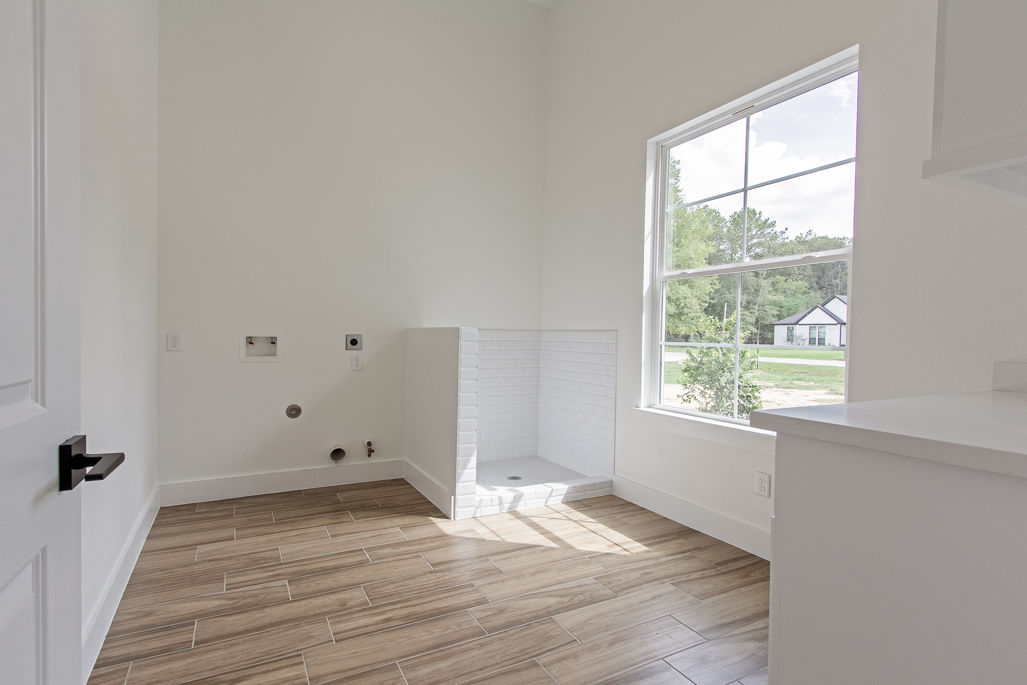 Utility room with tile shower and large window in a new Brixton custom home near Porter, TX